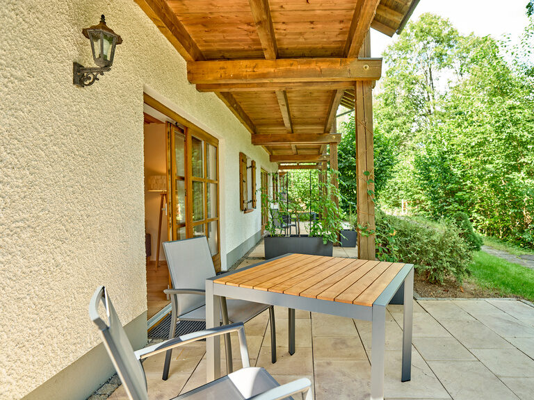 Terrasse einer Ferienwohnung im Landhaus Lerchenweg mit Tisch, Sitzmöglichkeiten und Ausblick ins Grüne